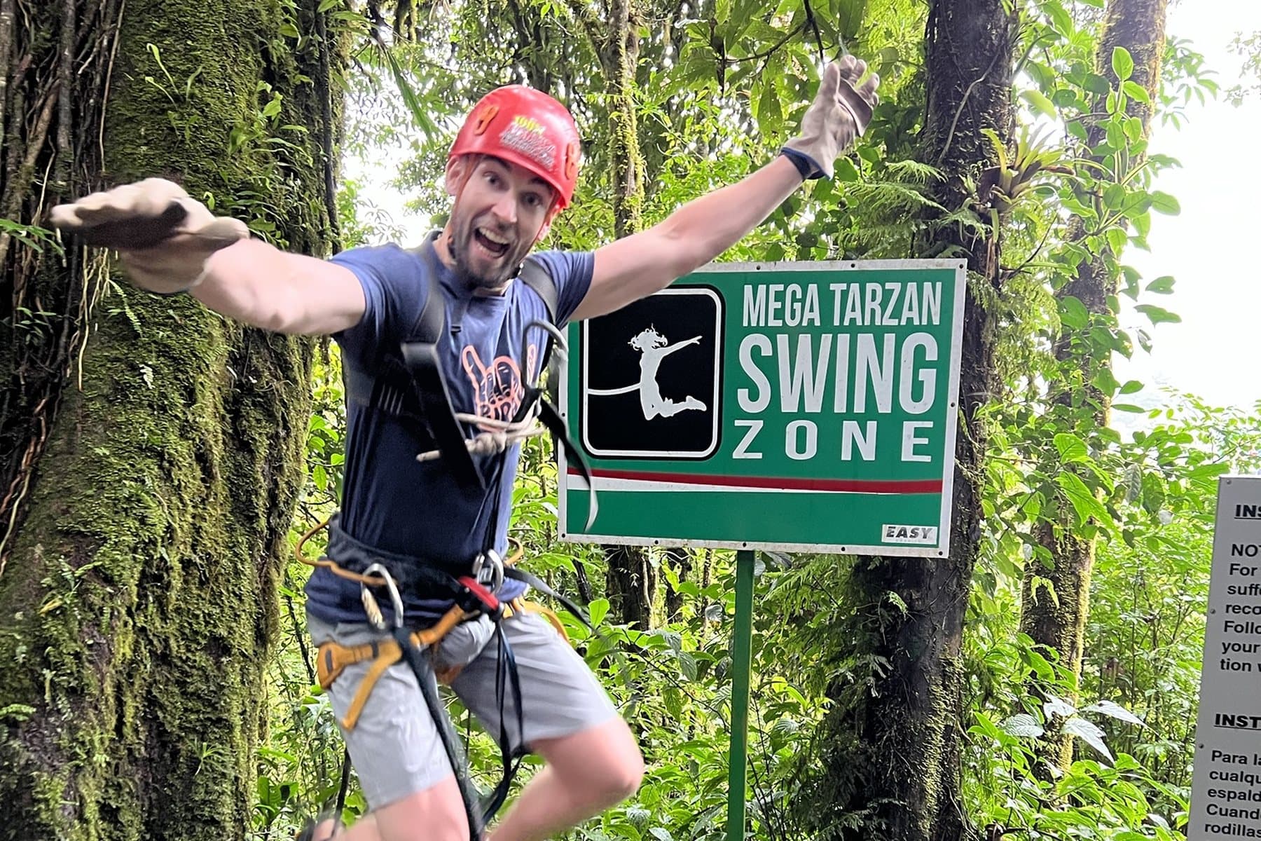Daniel leaping in a climbing harness at a rainforest canopy swing